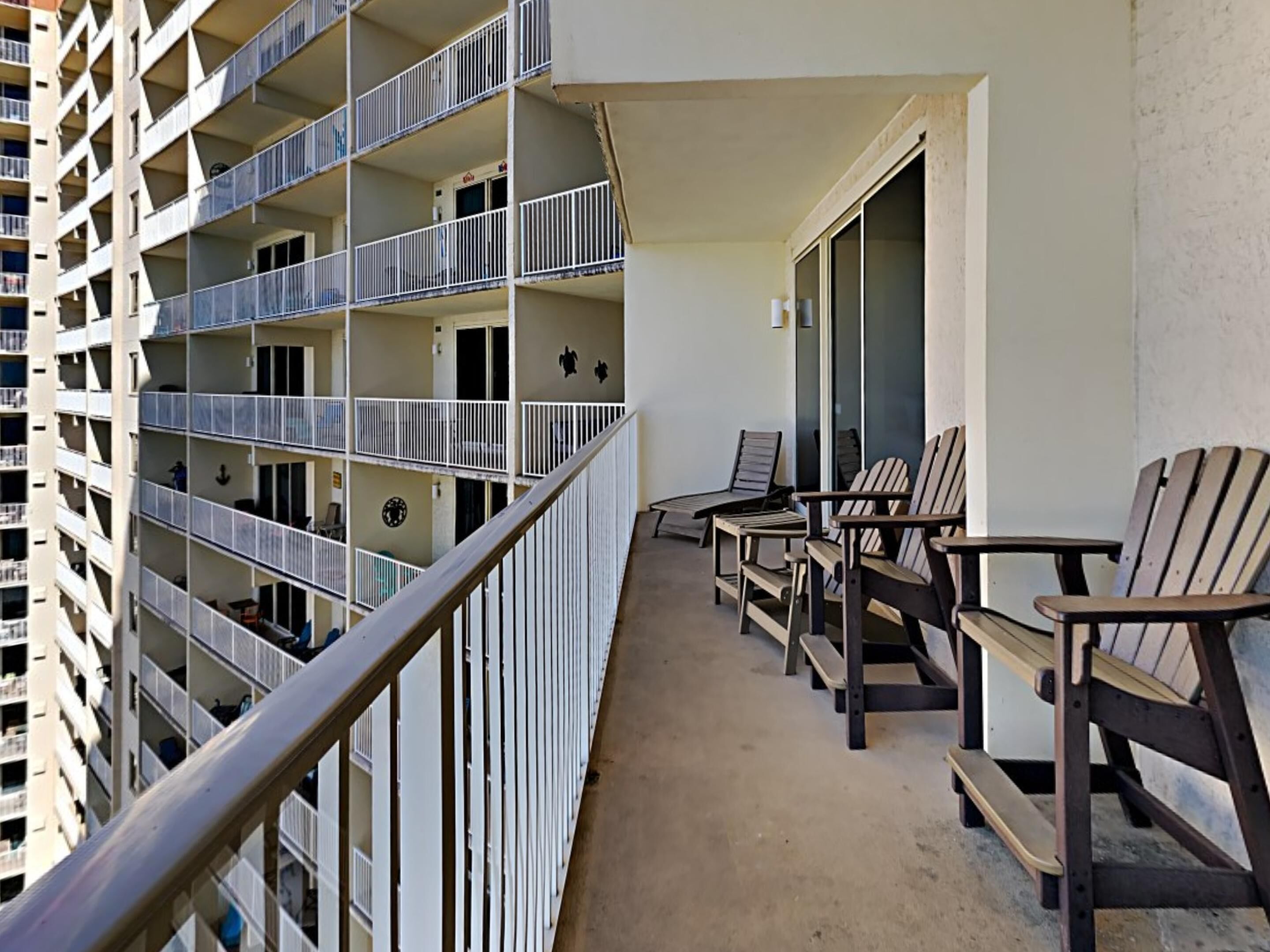 A multi-story residential building with balconies, each equipped with railings and a small table and chair.