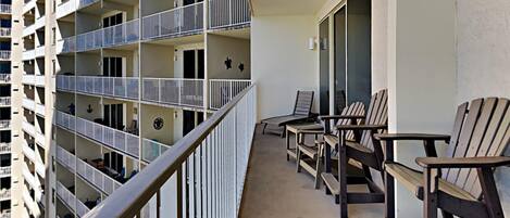 A multi-story residential building with balconies, each equipped with railings and a small table and chair.