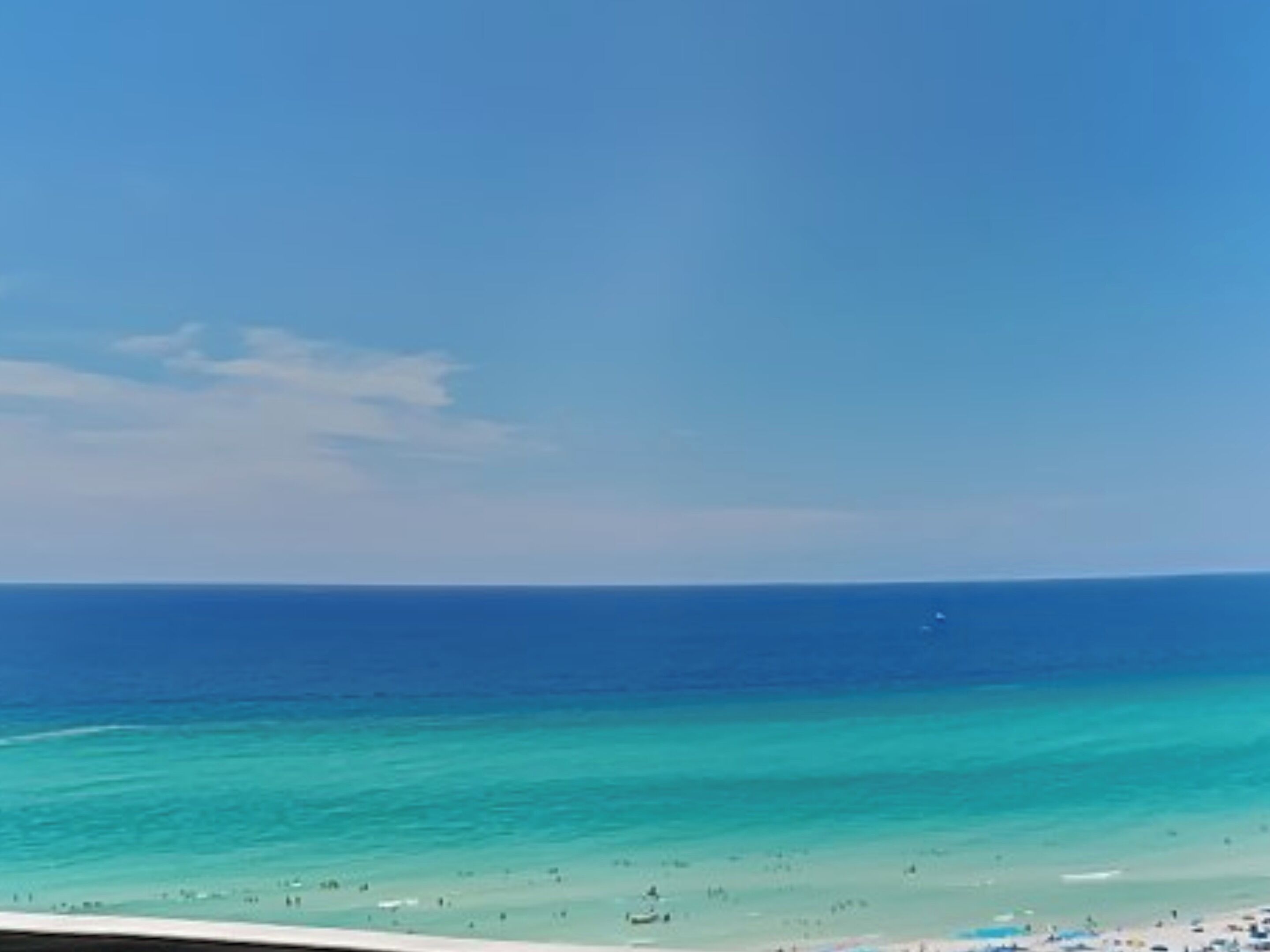 A beach with clear turquoise water and a sandy shore.