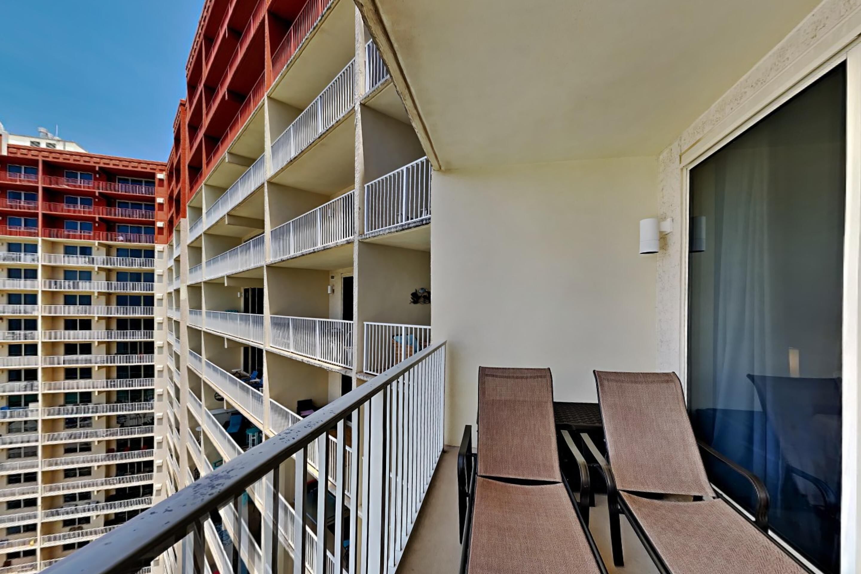 A balcony with two lounge chairs and a view of adjacent high-rise buildings.