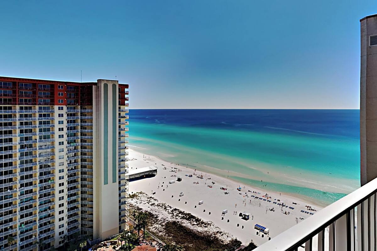 A high-rise hotel overlooking a beach with a clear view of the ocean and sandy shore.