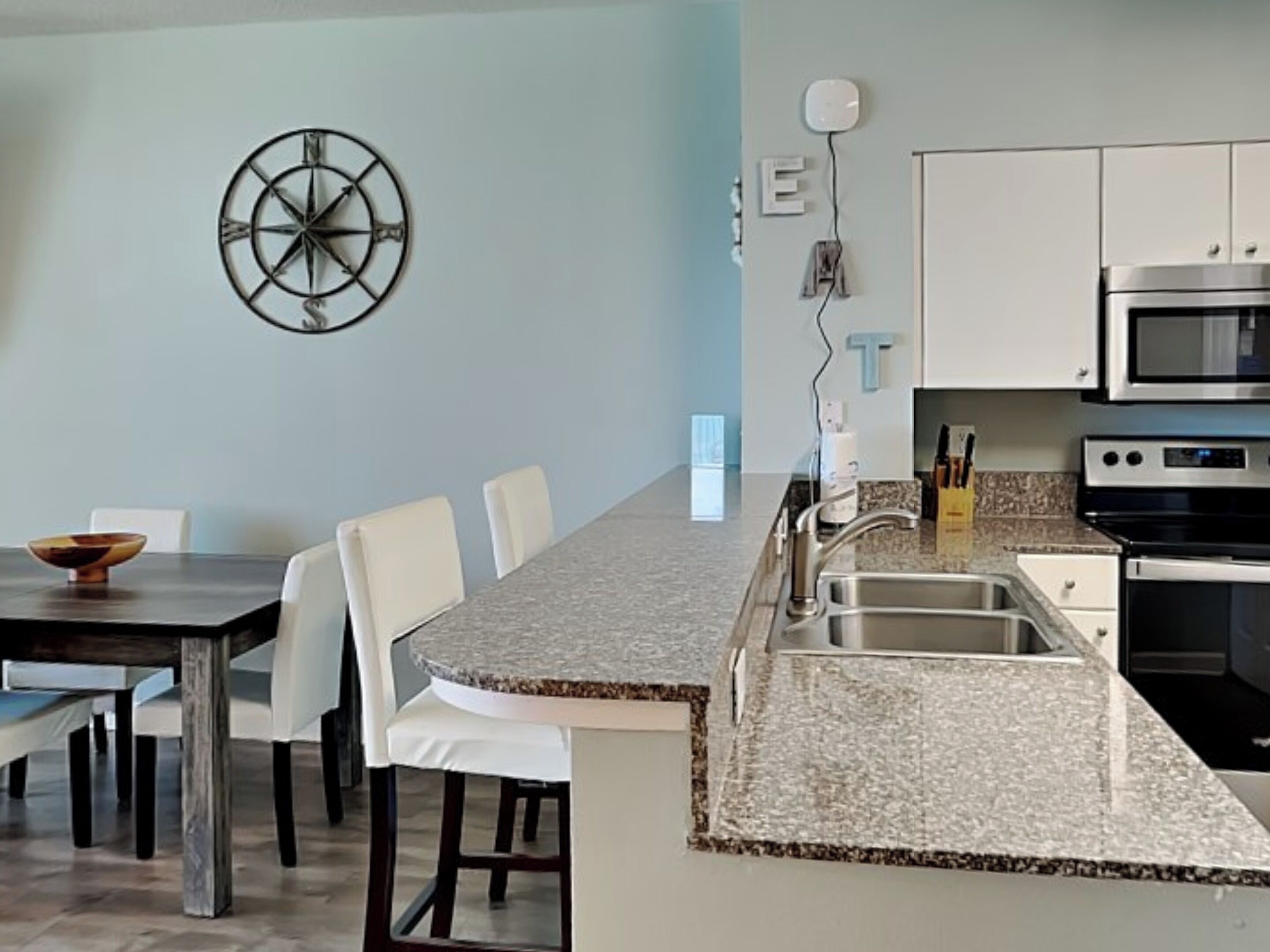 Una cocina moderna con armarios blancos, encimera de granito y electrodomésticos de acero inoxidable.
