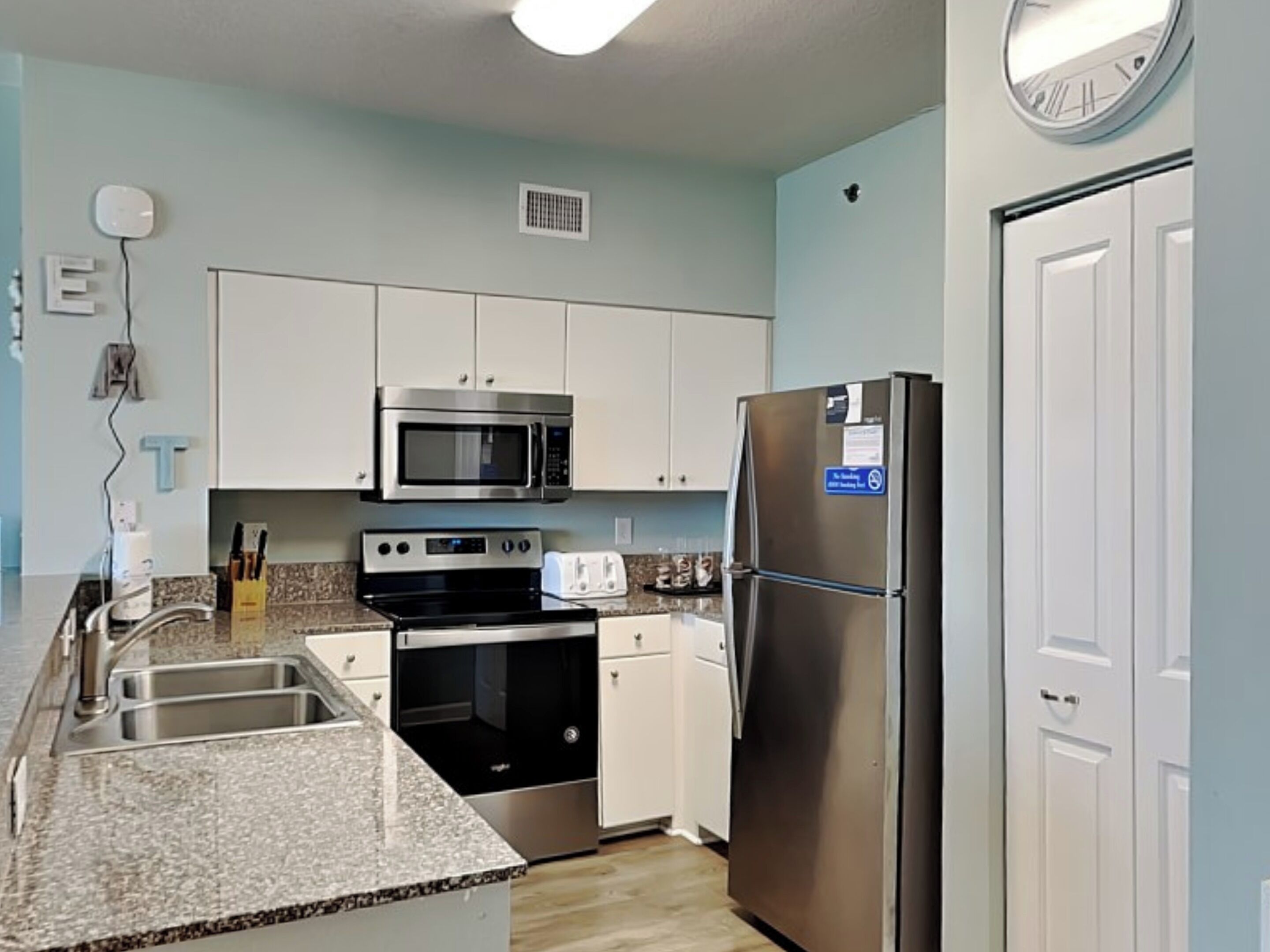 A modern kitchen with white cabinets, stainless steel appliances, and a granite countertop.