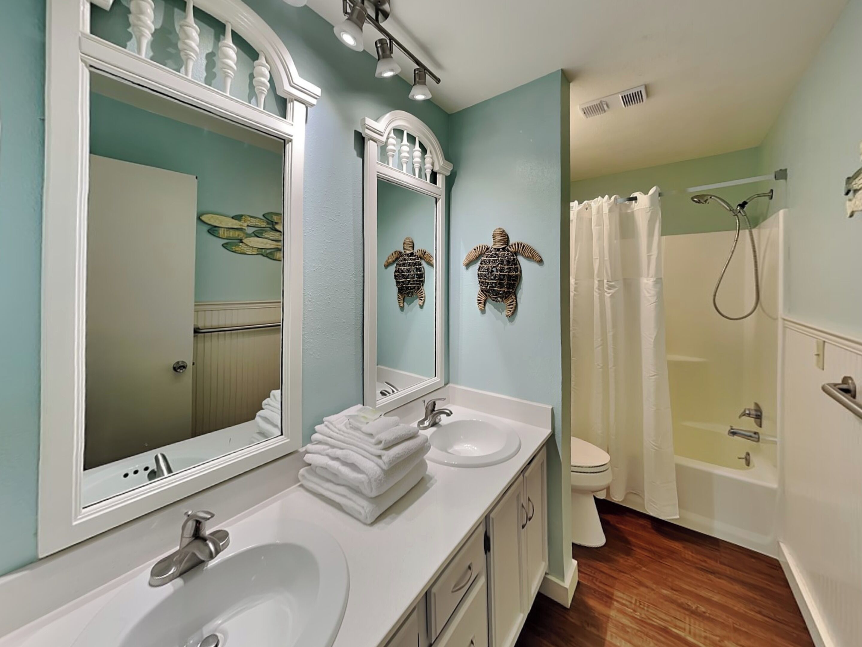 A bathroom with two sinks, a toilet, a shower, and a large mirror.