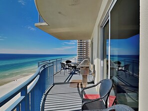 A balcony with a view of the ocean, a table, chairs, and a grill. - Sterling Breeze by Resort Collection (Panama City Beach)