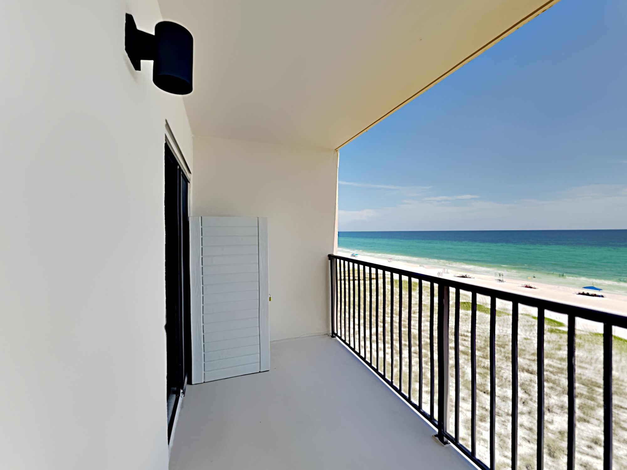 Een balkon met uitzicht op strand en zee.
