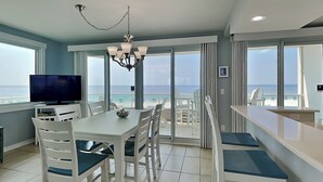 A dining area with a view of the beach, a chandelier, and a television. - Silver Beach by Southern Vacation Rentals (Orange Beach)