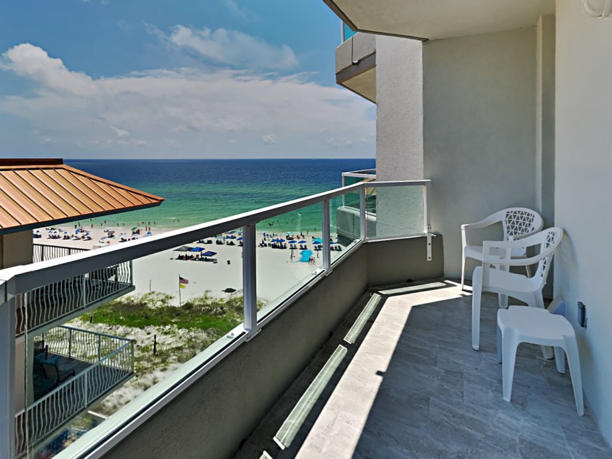 A balcony with a view of the beach and ocean.