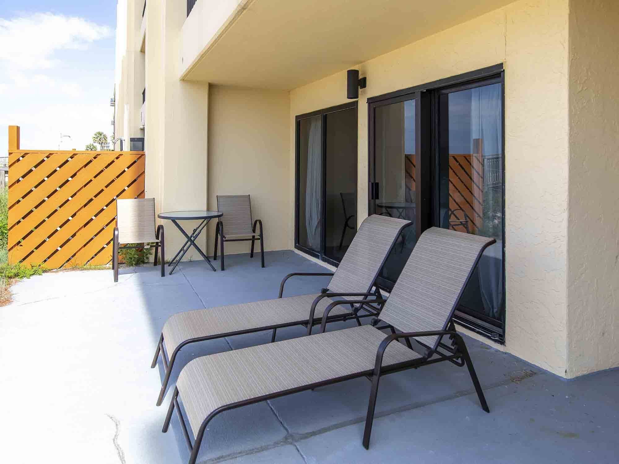 A patio with two lounge chairs, a small table, and a chair.