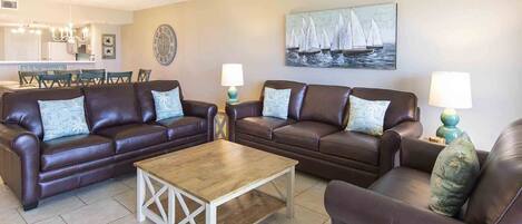 A living room with two brown leather sofas, a wooden coffee table, and two lamps.