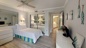 A hotel room with a bed, a desk, a television, and a ceiling fan. - Surf Dweller by Southern Vacation Rentals (Fort Walton Beach)
