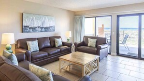 A living room with two brown leather sofas, a wooden coffee table, and a painting of sailboats on the wall. - Surf Dweller by Southern Vacation Rentals (Fort Walton Beach)