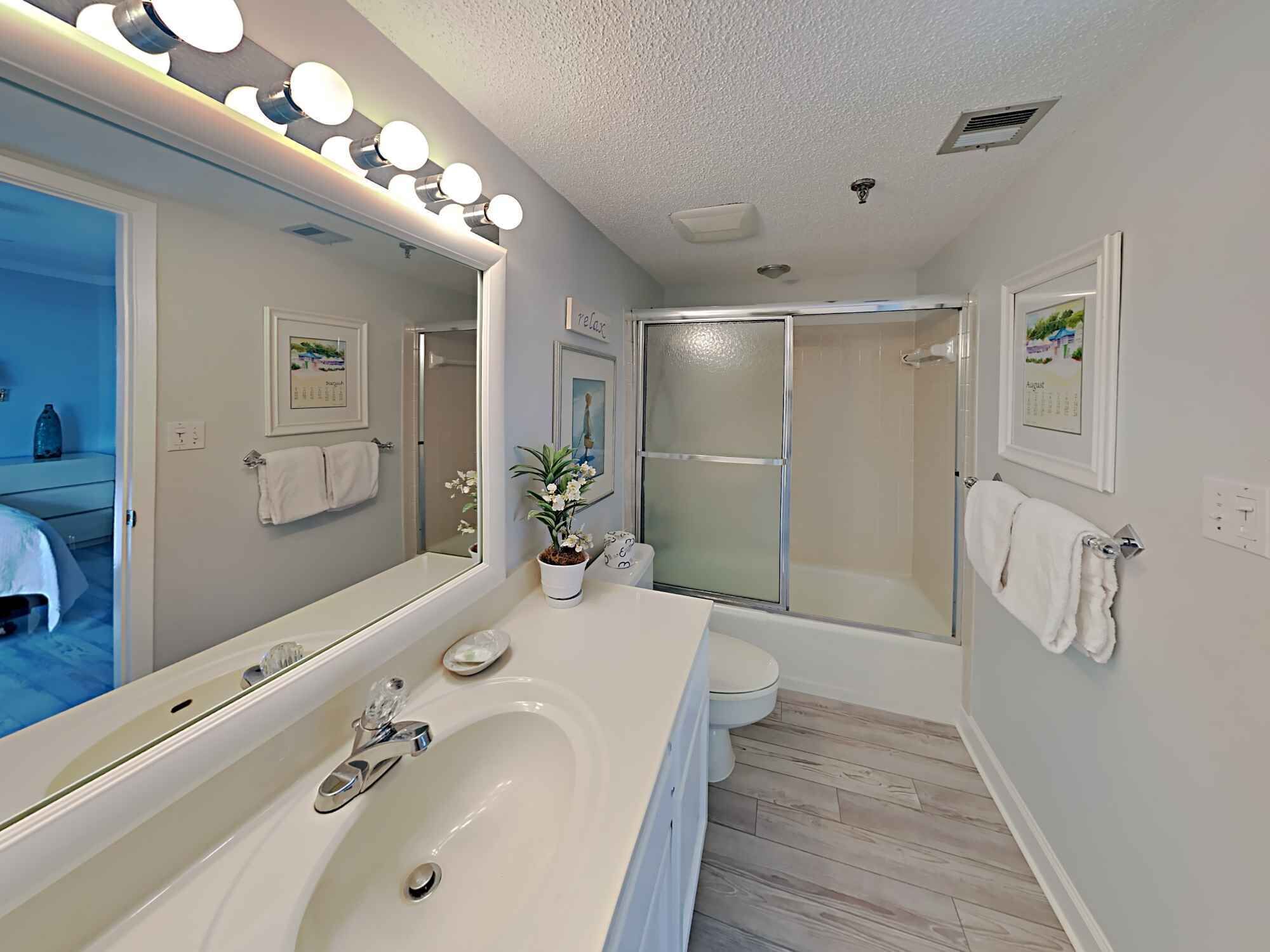 A modern bathroom with a large mirror, vanity, and a shower area.