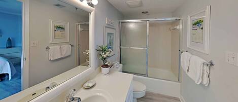 A modern bathroom with a large mirror, vanity, and a shower area.