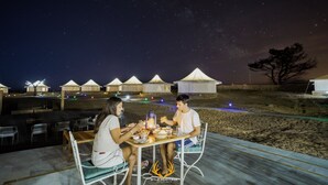 A couple dining at an outdoor table with a view of tents and a starry sky. - Wild Heritage Desert Camp Jaisalmer (Jaisalmer)