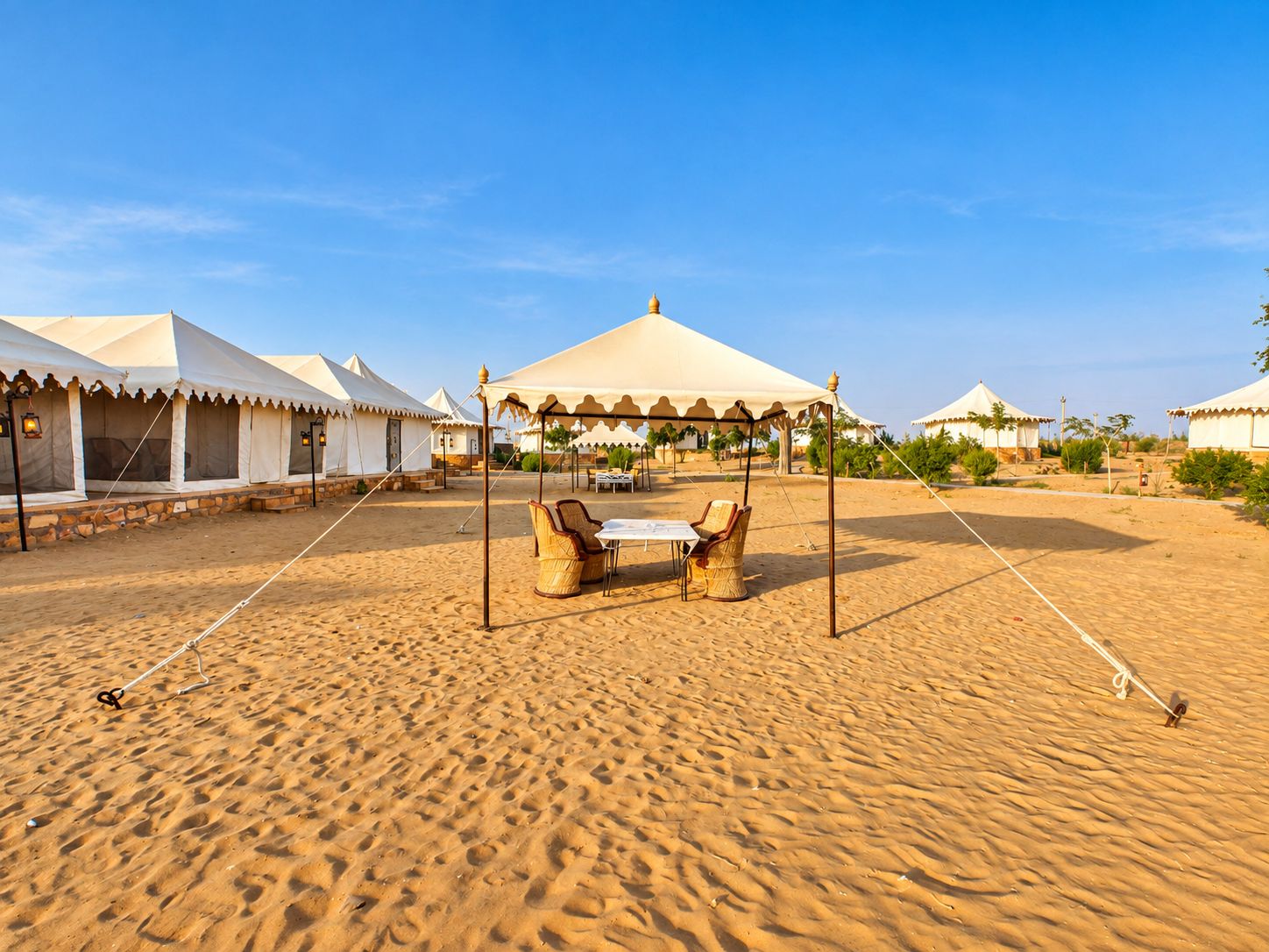 A desert campsite with tents and a table with chairs.