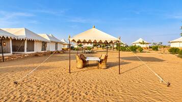 A desert campsite with tents and a table with chairs.