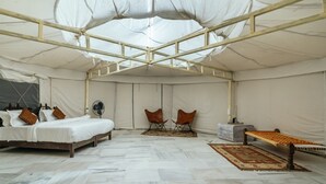 A tented room with a bed, two chairs, a bench, and a fan. - Wild Heritage Desert Camp Jaisalmer (Jaisalmer)