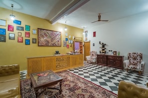 Eine Hotellobby mit Schachbrettfußboden, einer Rezeption und einer Sitzecke mit gemustertem Teppich.