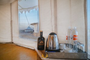 Un vassoio con una bottiglia di Jaisalmer Indian Craft Gin, una caffettiera, tazze e bottiglie d'acqua, all'interno di una tenda.