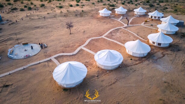 An aerial view of a desert resort with yurts connected by pathways, a central gathering area, and sparse vegetation. - Wild Heritage Desert Camp Jaisalmer (Jaisalmer)