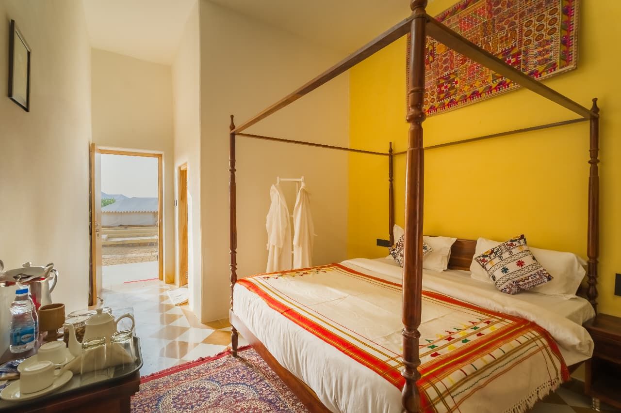 Ein Bett mit Baldachin, ein Schachbrettmuster auf dem Boden, ein Tisch mit Teeservice und Blick ins Freie.