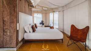 A spacious tented room with a large bed, a wooden floor, and a fan. - Wild Heritage Desert Camp Jaisalmer (Jaisalmer)