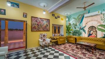 A living room with a checkered floor, a sofa set, a patterned rug, and a mural on the wall.