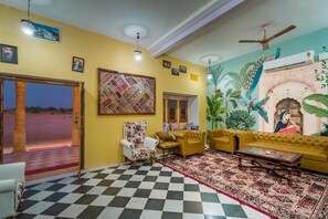 Una sala de estar con suelo a cuadros, un conjunto de sofás, un tapiz estampado y un mural en la pared.