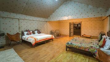 Una habitación con dos camas, una silla, una mesita y una puerta que da a otra habitación.