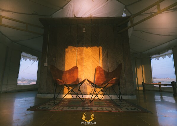 Una habitación con carpa, un ventanal grande, dos sillas y una alfombra.