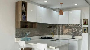 A modern kitchen with a central island, white cabinetry, and a backsplash with hexagonal tiles. - 1 Bed Flat - Sleeps 2 - Parking - Wifi (Tunis)