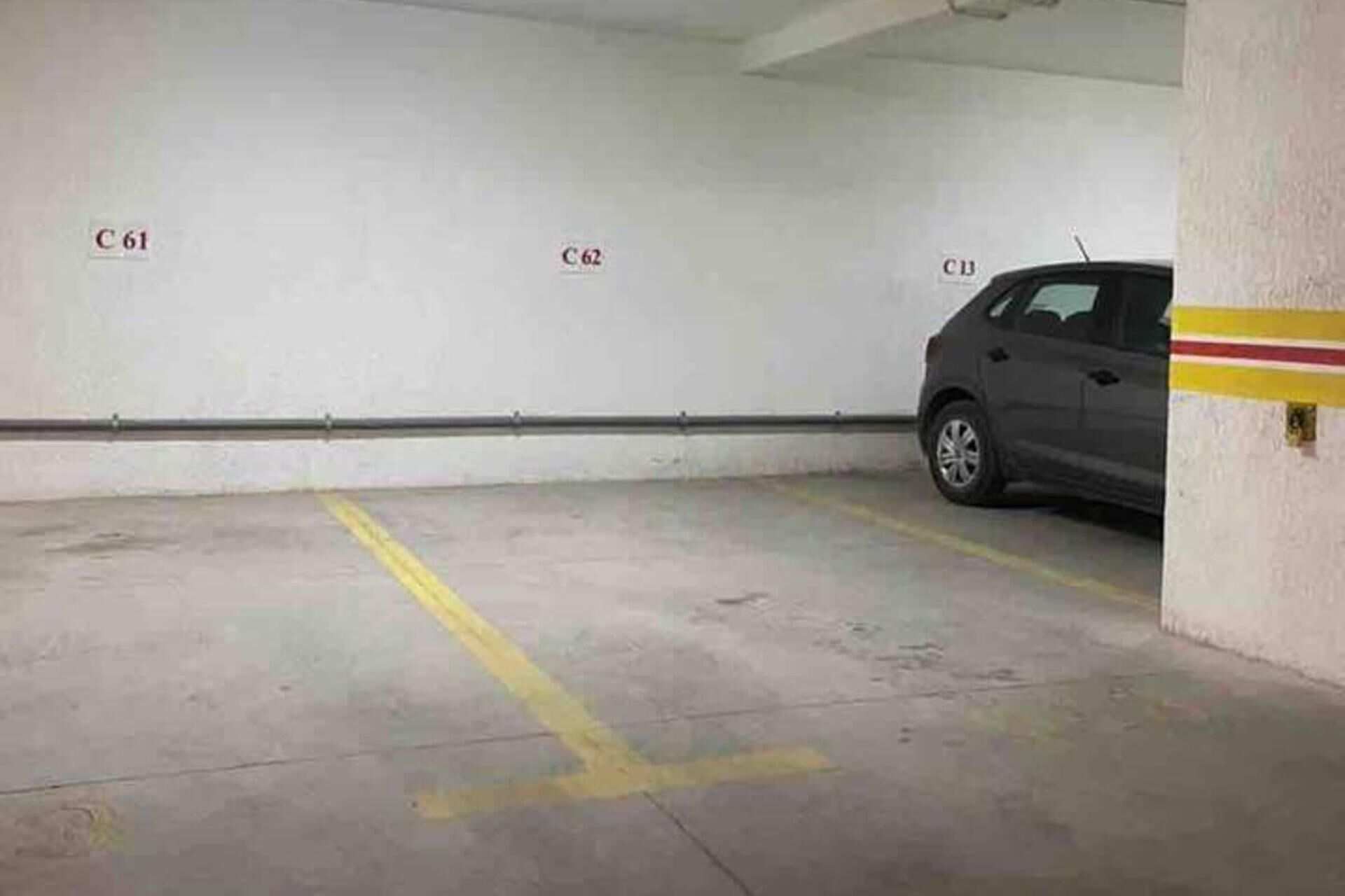 Un parking souterrain avec des places de stationnement délimitées et une voiture garée sur l’une d’elles.