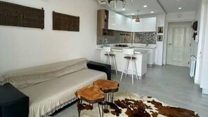 A modern living room with a sofa, a cowhide rug, and a kitchen in the background. - 1 Bed Flat - Sleeps 2 - Parking - Wifi (Tunis)
