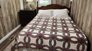 Un dormitorio con una cama de madera, una mesita de noche con lámpara y una ventana con cortinas.