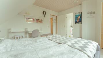 Ein Schlafzimmer mit Bett, Schreibtisch und Stuhl. Eine Tür führt in einen weiteren Raum.