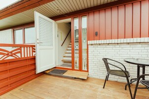 Una terraza de madera con un ventanal de vidrio que da a una escalera.
