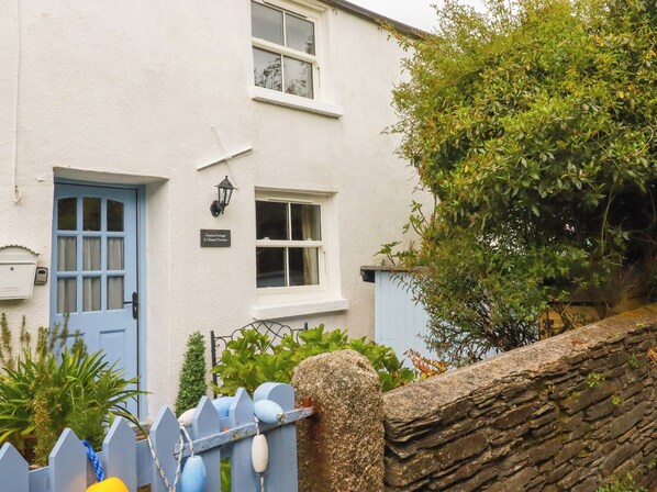 A white building with a blue door, a small window, and a sign reading 'Granny Cottage 3, Chapel Terrace.'