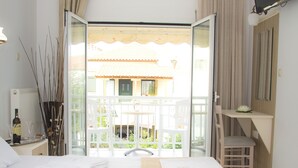 Ein Hotelzimmer mit zwei Betten, einem Balkon, einem Fernseher und einem Schreibtisch.
