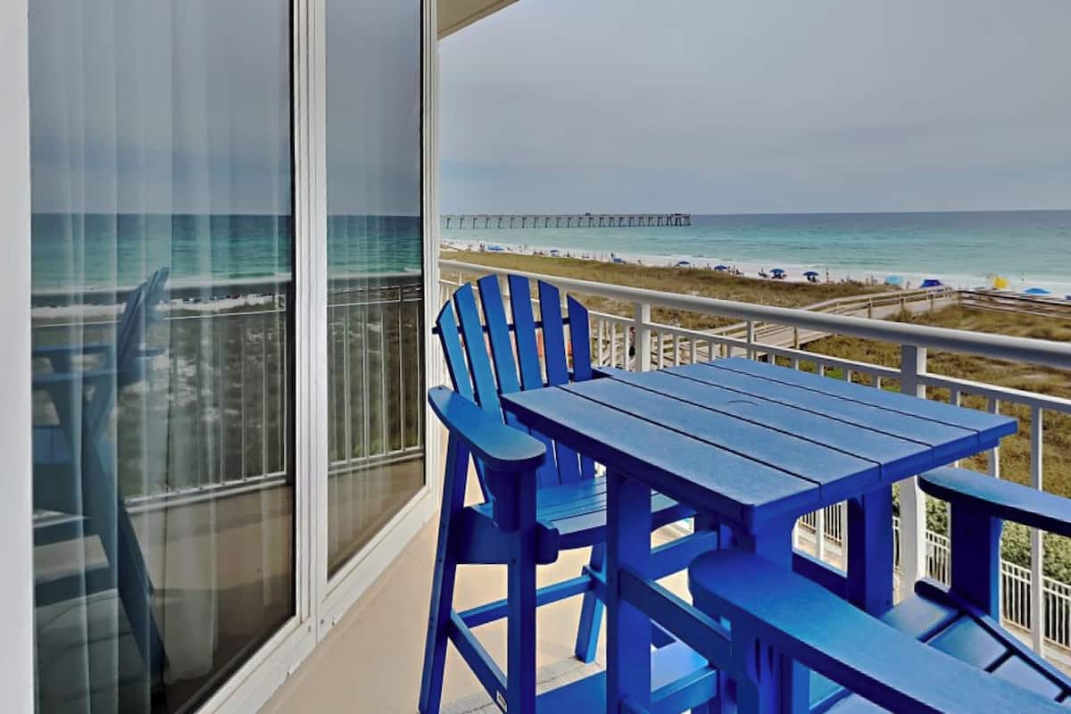 A balcony with a view of the ocean and a pier.