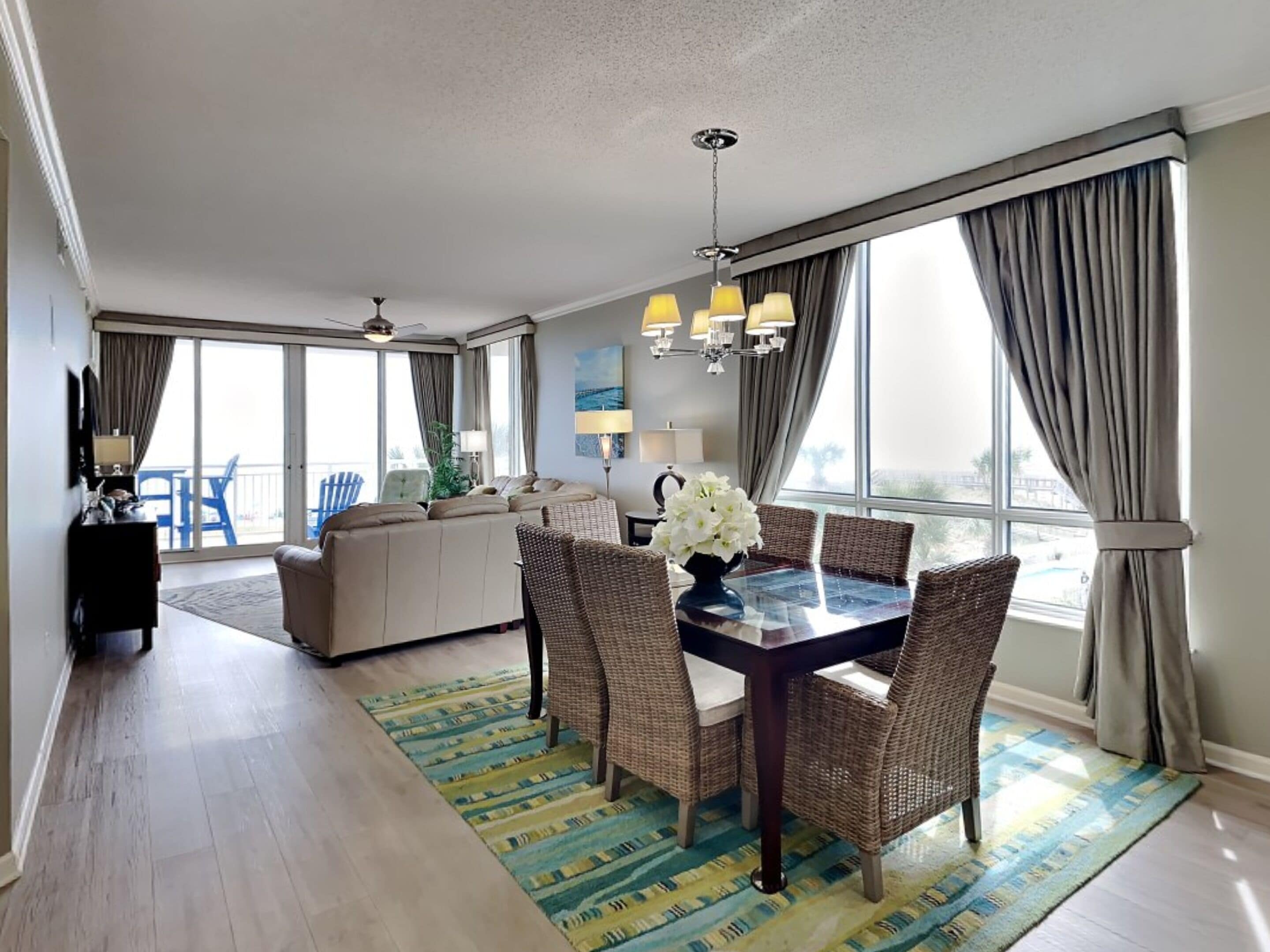 A spacious living room with a dining area, large windows, and a balcony.