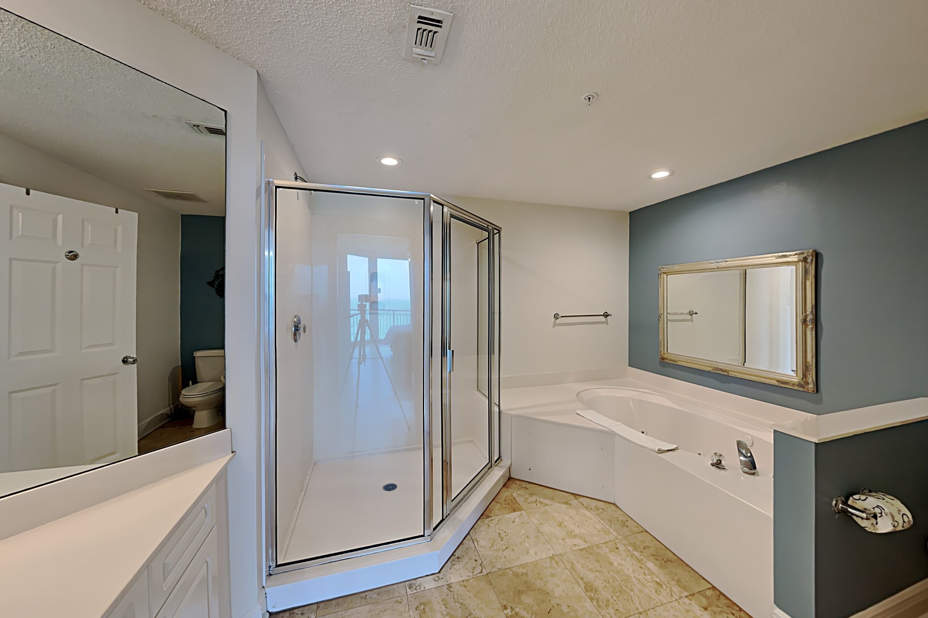 A modern bathroom with a glass-enclosed shower, a white bathtub, and a large mirror.