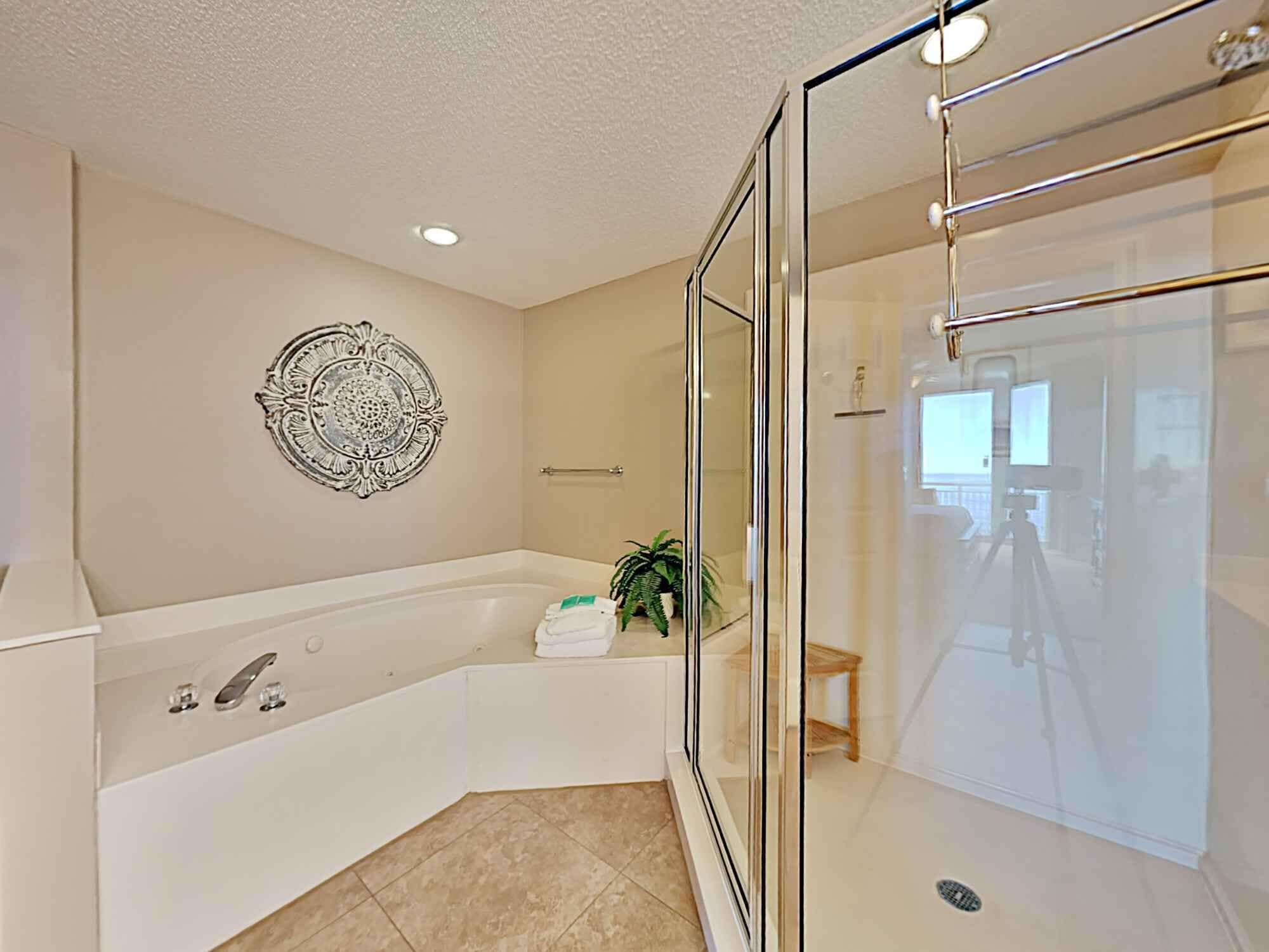 Un baño moderno con una bañera independiente, cabina de ducha con paredes de vidrio y un elemento decorativo en la pared.