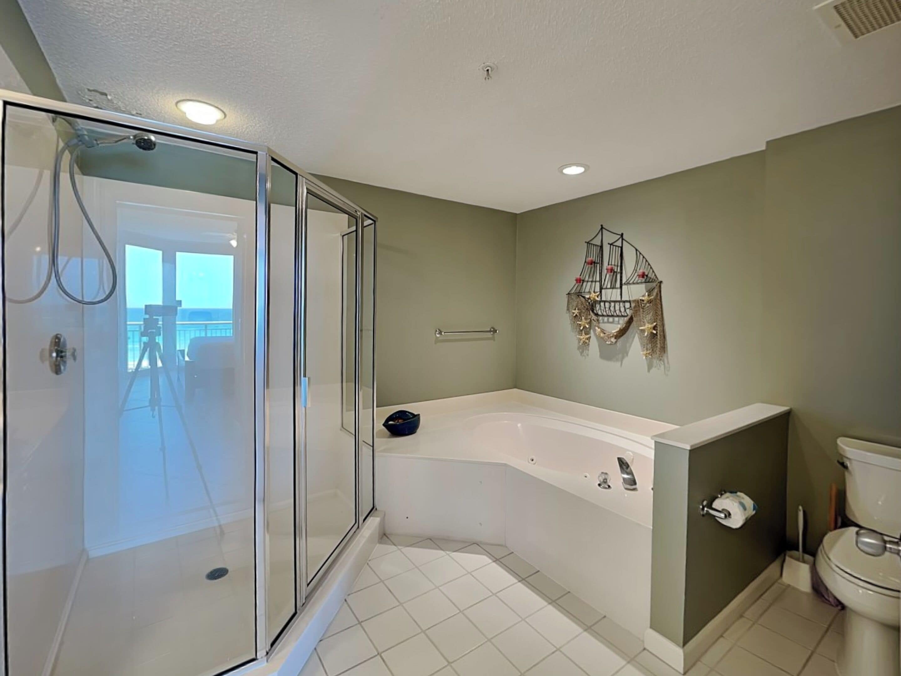 A bathroom with a glass-enclosed shower, a large bathtub, and a toilet.