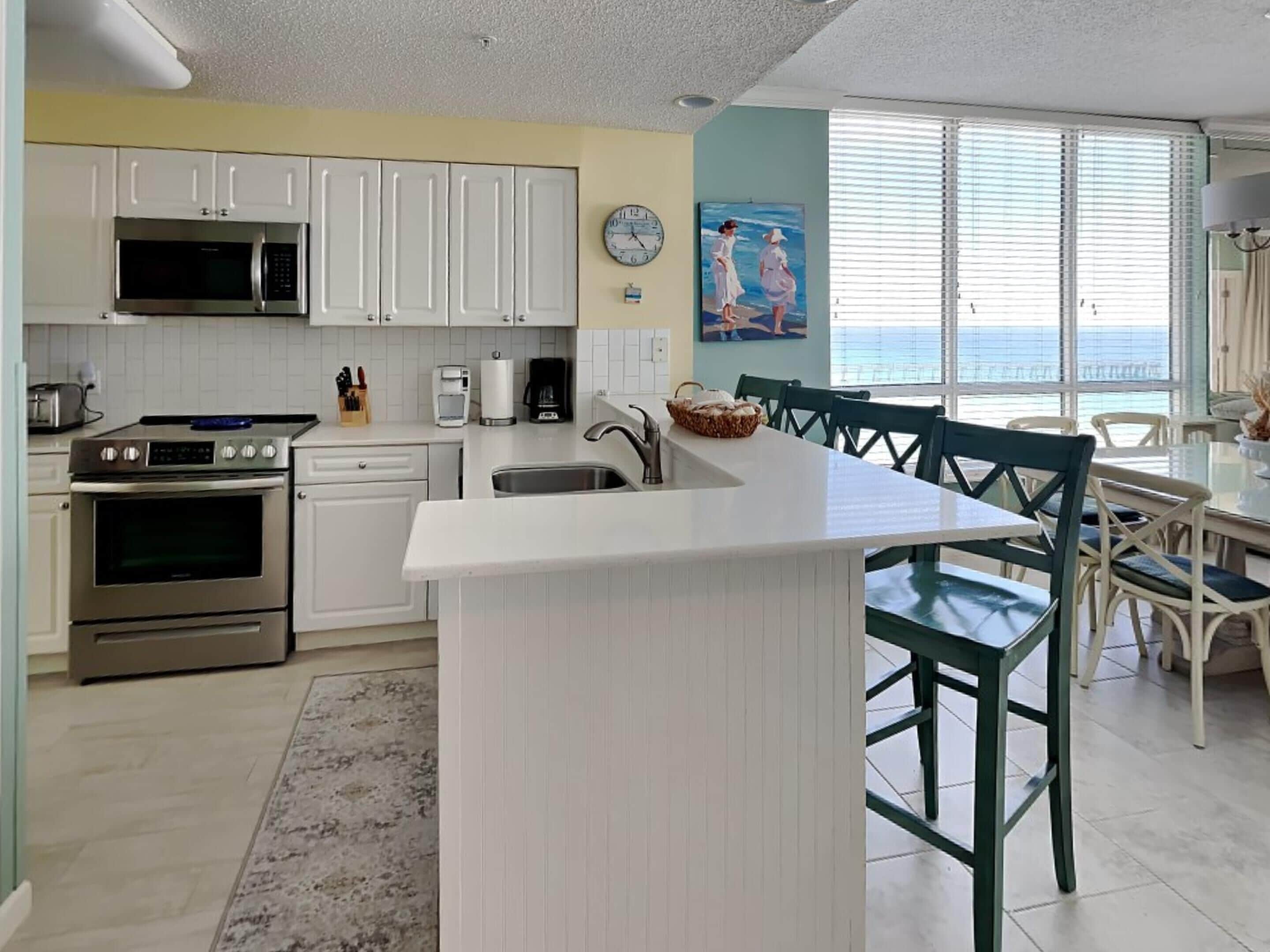 A modern kitchen with white cabinets, stainless steel appliances, and a large island with bar stools.