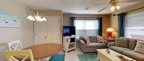 A living room with a TV, sofa, and dining area.