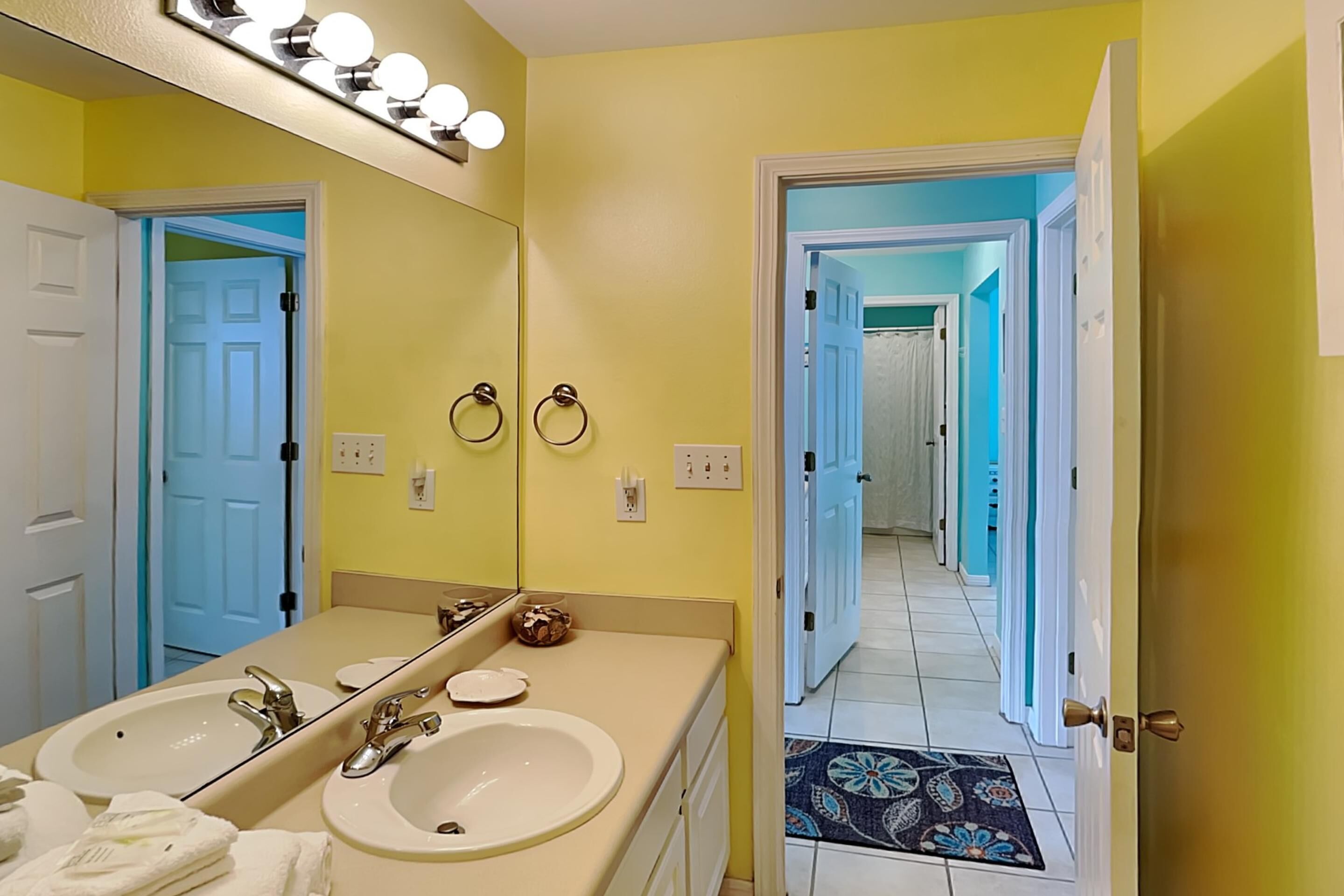 A bathroom with two sinks, a large mirror, and a lighted vanity.