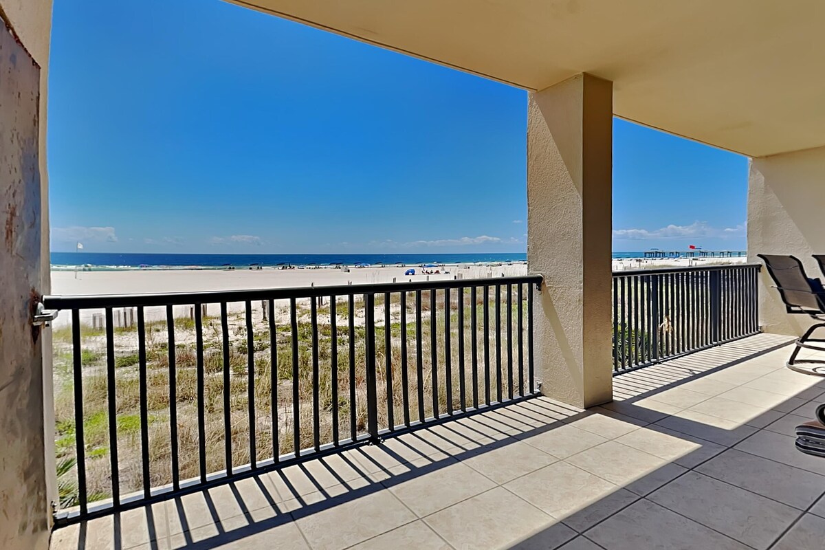 A balcony with a view of the beach and a pier.