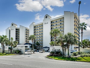 A multi-story hotel with a prominent 'The Palms' sign, featuring a modern architectural design with balconies and a parking area in front.