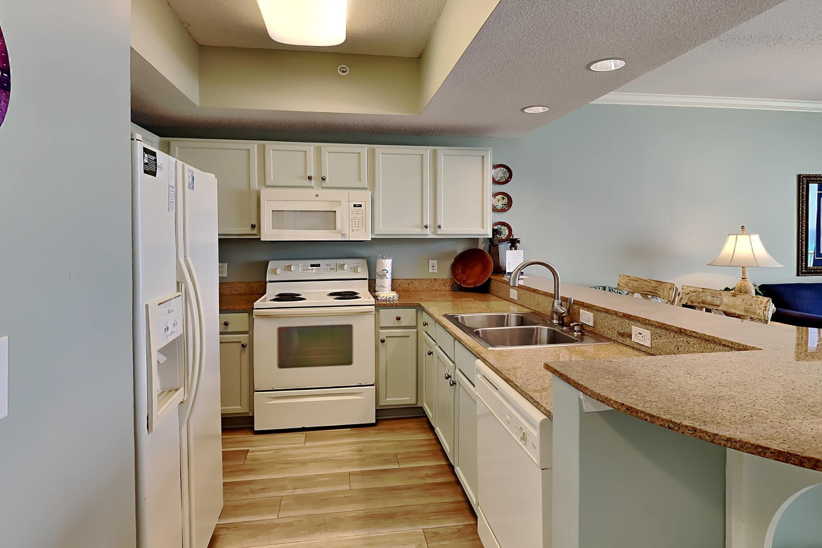 A kitchen with white cabinets, a microwave, a stove, and a sink.